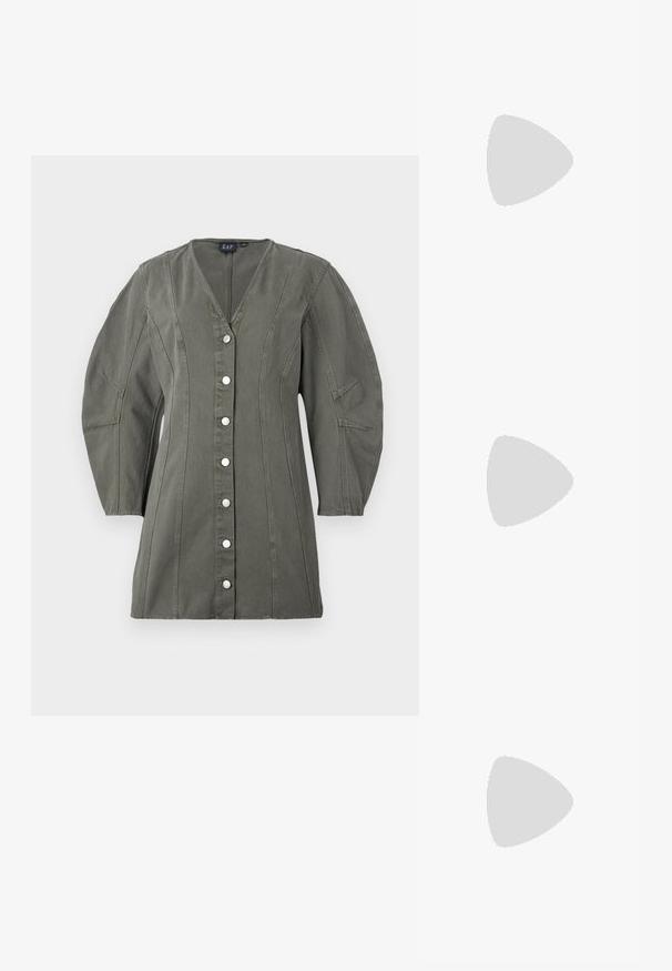 Giacca verde oliva con bottoni, scollo a V, maniche a sbuffo e cuciture verticali. Presenta bottoni argentati e una forma strutturata.; Mocassini platform neri in pelle con punta arrotondata e fascia larga sulla tomaia. Presentano un tacco spesso e quadrato e una texture liscia.; Donna con lunghi capelli scuri, vestita con un completo nero, che porta una borsa a tracolla in pelle nera, mentre guarda oltre la spalla su uno sfondo bianco.; Orecchini a cerchio in argento con un design minimalista. Forma circolare, superficie liscia e profilo sottile. Leggeri con una finitura lucida.