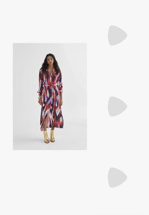 Lunga vestito trasparente con un motivo astratto colorato in rosso, viola e nero. Presenta un colletto, vita con cintura e spacchi laterali. Indossato con stivaletti oro alla caviglia.; Sandali in pelle vegana dorata con due cinturini regolabili, soletta in sughero e suola in gomma scura. Texture liscia con finitura metallica.; Occhiali da sole rettangolari con montatura in plastica tartarugata, lenti scure e dettagli argentati sui lati. Made in Italy.; Borsa a tracolla in pelle marrone con motivo logo, tracolla in catena dorata, chiusura con zip e dettagli in metallo dorato. Forma compatta e rettangolare.