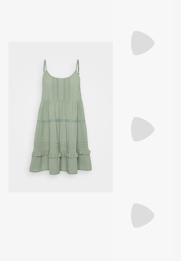 Abito senza maniche di un verde chiaro con un design svasato, caratterizzato da dettagli in pizzo e volani arricciati, rifinito con accenti a orlo a rouches.; Pump in pelle nera con punta affusolata e tacco basso a blocco. Presenta una cinghia alla caviglia con una fibbia in tonalità oro. Texture liscia.; Occhiali da sole neri oversize con lenti sfumate, montatura spessa e dettagli in catena dorata sulle astine.; Borsa nera con forma strutturata, texture liscia e una chiusura metallica. Abbinata a pantaloni neri larghi e sandali open-toe su un pavimento in legno.