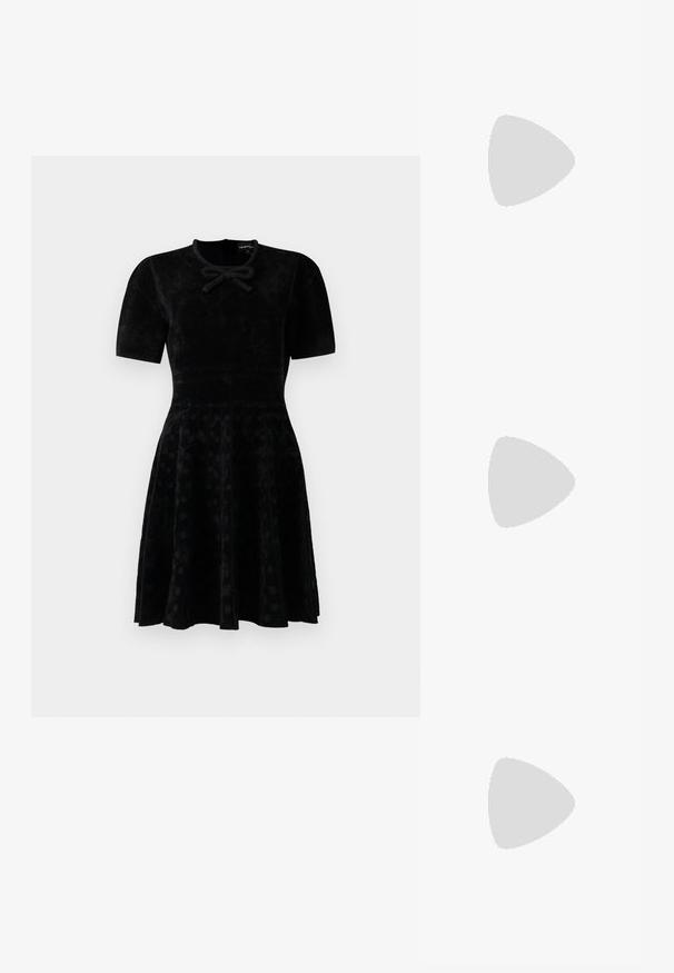 Abito in velluto nero a maniche corte con vita aderente, gonna svasata con sottili pois e un piccolo dettaglio a fiocco sullo scollo.; Sneakers in pelle bianca, design low-top, caratterizzati da una texture liscia, punta rotonda, chiusura con lacci e un piccolo logo ricamato sul lato.; Borsa a mezzaluna nera in pelle con dettagli in hardware dorato, dotata di chiusura con zip. Indossata a tracolla sopra un maglione grigio.; Orecchini a perno in tono oro con design intrecciato. Ogni orecchino presenta uno sfondo circolare trasparente per una vestibilità sicura.