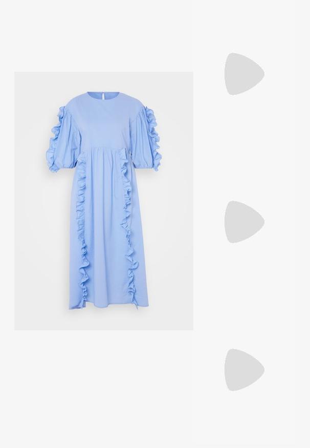Lys blå midi kjole lavet af blødt stof med puffærmer og flæsede detaljer langs fronten og siderne. Nøgnehul bagdetalje.; Beige hæl sandal med en klar rem, blokhæl og lange frynse accenter ved anklen. Glat materiale med et minimalistisk design.; Metallic sølv bucket bag med en tekstureret overflade, prydet med et sølv rundt håndtag og snørelukning, holdt mod lyseblå jeans.; Fire sølv ringe med forskellige designs: snoet band, lagdelte kurver, delikate krystaller og et glat band med små detaljer.