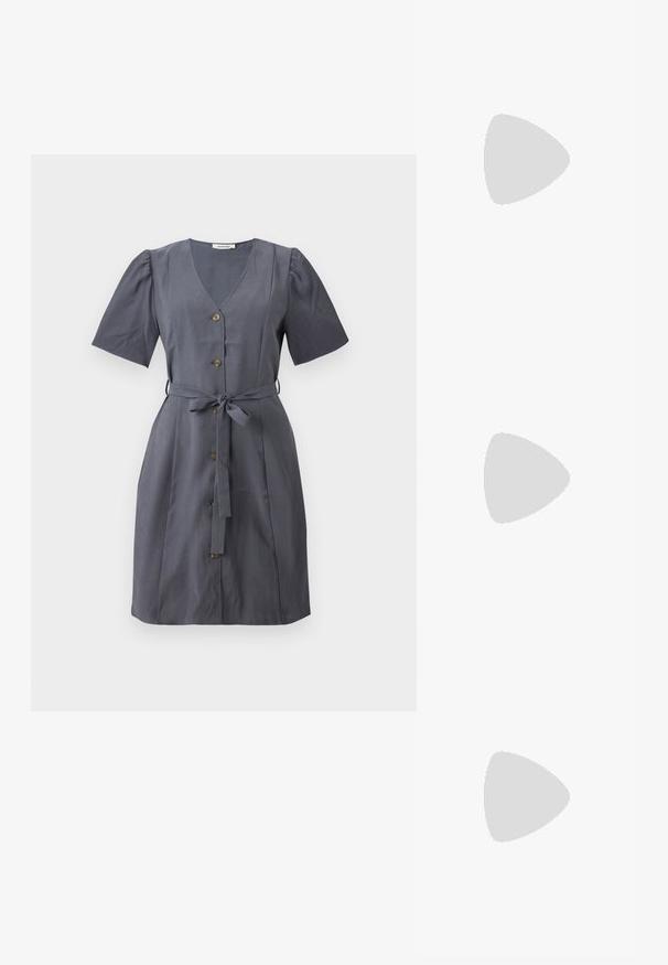 Vestido cinza com decote em V, mangas curtas bufantes, botões frontais e um cinto de tecido. Textura suave e desenho até ao joelho.; Sabrinas de cerâmica preta com salto bloco, bico apontado e um design com recortes arredondados. Apresenta um detalhe em fivela de tom dourado.; Óculos de sol oversized pretos com lentes degradê, armações grossas e detalhes em corrente dourada nas hastes.; Bolsa preta com forma estruturada, textura suave e um fecho metálico. Combinada com calças largas pretas e sandálias de salto aberto sobre um chão de madeira.