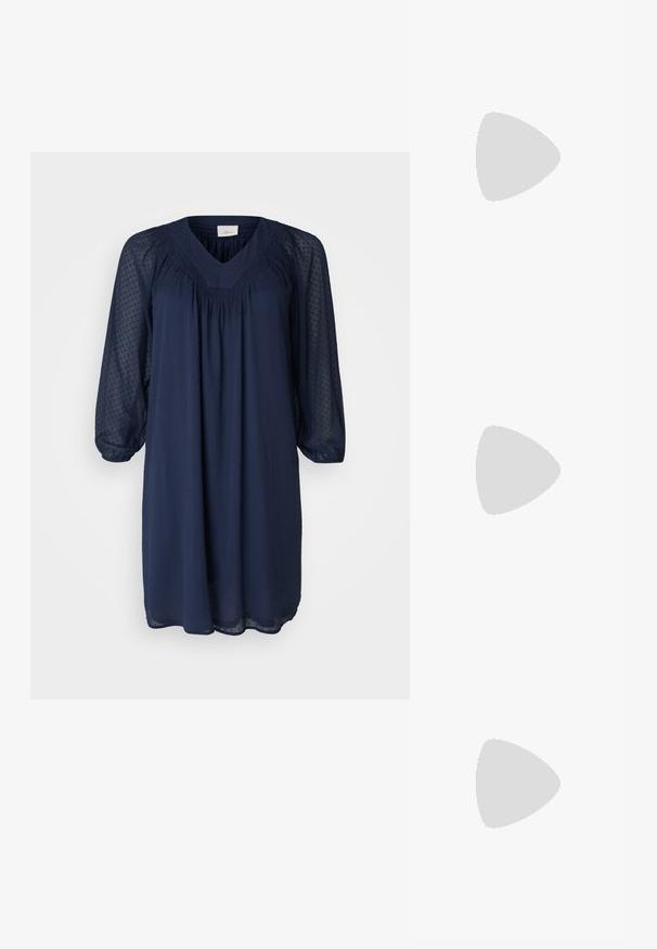 Mornarsko moder obleko z V-izrezom, dolgimi prosojnimi rokavi in nagubanimi detajli na korpusu. Teksturovana tkanina s pikčasto vzorcem.; Črne usnjene balerinke, koničast toe, minimalističen dizajn, gladka tekstura, nizka peta, brez vidnih kovinskih delov ali okraskov.; Črna usnjena torba s gladko teksturo, strukturirano obliko, dvema ročkama in izrazitim srebrnim sponko na sprednji strani.; Srebrn dvojni prstan z gladko, polirano površino. Ima tekoč, ukrivljen dizajn z prekrivajočimi se sekcijami za sodoben videz.