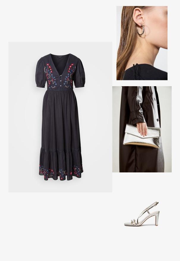 Robe maxi noire avec des manches courtes évasées, décolleté en V profond, ornée de broderies florales colorées sur le buste et l'ourlet. Tissu doux et fluide.; Sandale à talon haut en métal argenté avec un bout ouvert, dotée de trois fines lanières sur le pied et d'une lanière autour de la cheville avec une boucle.; Pochette métallique argentée avec un design d'enveloppe angulaire, texture lisse et couleur intérieure contrastante, tenue dans une main portant un manteau noir.; Boucle d'oreille en argent avec une finition polie, présentant de petits détails en or et de forme ronde, portée sur le lobe.