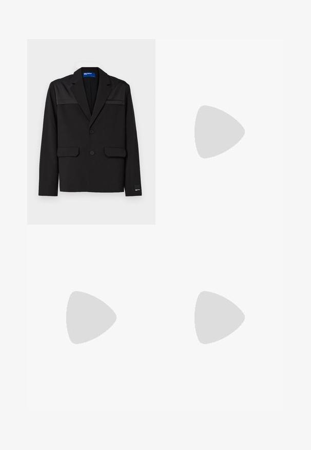 Blazer nero con un design strutturato, due tasche frontali, due bottoni e accenti lucidi sulle spalle. Realizzato in un tessuto morbido.; T-shirt bianca a maniche corte in cotone con un piccolo design grafico nero e beige che rappresenta un volto con occhiali da sole sul davanti.; Pantaloni neri con vita regolabile tramite cordoncino, caratterizzati da due pieghe frontali, design a gamba dritta e senza motivi o dettagli hardware visibili.; Scarpa in pelle nera con punta arrotondata, dettaglio con fibbia singola e suola in gomma piatta. Presenta un marchio sul lato vicino al tallone.