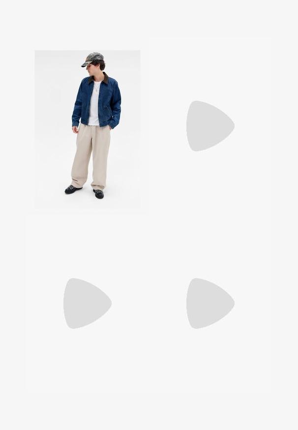 Jovem a usar um boné de camuflagem, jaqueta de ganga azul, camisa branca, calças largas bege, sapatos pretos e um colar de cruz dourado, posando contra um fundo branco.; Camisa branca de mangas longas com botões, feita de um tecido liso. Apresenta um colarinho clássico, botões na frente e punhos com um botão. Design ajustado.; Jeans de denim cinza escuro com corte reto, apresentando cinco bolsos, fecho de botão e detalhes de costura sutis.; Sandalho oxford de couro preto com design de atacador, bico arredondado, sola de borracha plana e detalhe de costura discreto no cabedal.