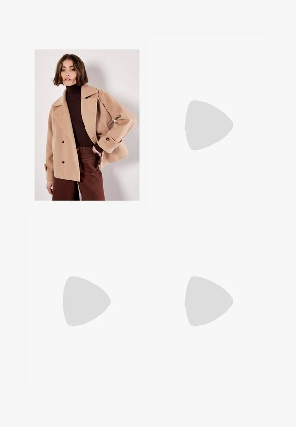 Frau mit kurzen braunen Haaren, die einen beigen doppelreihigen Mantel über einem dunkelbraunen Rollkragenpullover und dunkelbraunen Hosen trägt, posiert vor einer weißen Wand.; Cremfarbener V-Ausschnitt-Pullover aus weichem Strickmaterial; mit langen Ärmeln und gerippten Bündchen und Saum. Keine sichtbaren Muster oder Beschläge.; Weiße lässige Jeans aus Denim mit hochgeschnittenem Bund, Fronttaschen und Knopfverschluss. Schlichtes Design mit minimalen Akzenten.; Beige Knöchelboots mit spitzem Zehenbereich, aus glattem Material gefertigt, mit transparentem Blockabsatz und minimalistischem Design.; Braune Wildleder-Schultertasche mit weicher Textur, geschwungenem Oberteil und verstellbarem Riemen mit Metallakzenten. Schlichtes, minimalistisches Design.