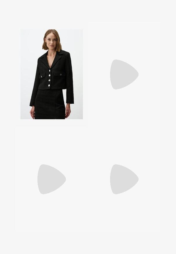 Schwarze (kurz geschnittene) Jacke aus strukturiertem Stoff mit Spitzkragen, zwei vorderen Taschen und fünf großen silberfarbenen Knöpfen.; Schwarzes ärmelloses Oberteil aus glattem Stoff, mit einem runden Ausschnitt und einer figurbetonten Passform, ohne sichtbare Muster oder Verzierungen.; Schwarze Hose mit geradem Schnitt, ausgestattet mit Fronttaschen und Seitenschlitzen am Saum. Hergestellt aus weichem, glattem Stoff. Geeignet für verschiedene Anlässe.; Schwarze patentierte Sandalen mit Absatz, quadratischer Spitze, Knöchelriemen und silbernen Schnallen. Mit einem stabilen Blockabsatz für mehr Stabilität.