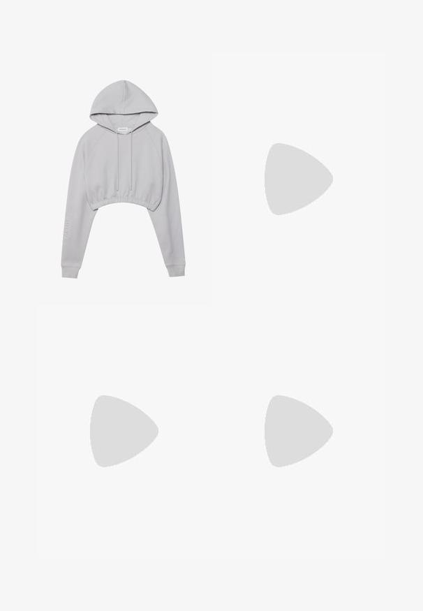 Lys grå cropped hettegenser med snor i hetten, raglanermer, ribbet kant og teksten "ACTIVE" på den ene ermen.; Ribbede blyantskjørt i lys lilla med en tettsittende design. Har høy midje, glatt tekstur og knelengde.; Hvit sneaker laget av mesh og lær, rund tå, tykk såle, fremtredende lisser, og merkevare på hælen og tungen.; Svarte rektangulære solbriller med tykke rammer, med detaljer i gull. Modellen har på seg en lys beige ribbestrikket høyhalset topp.