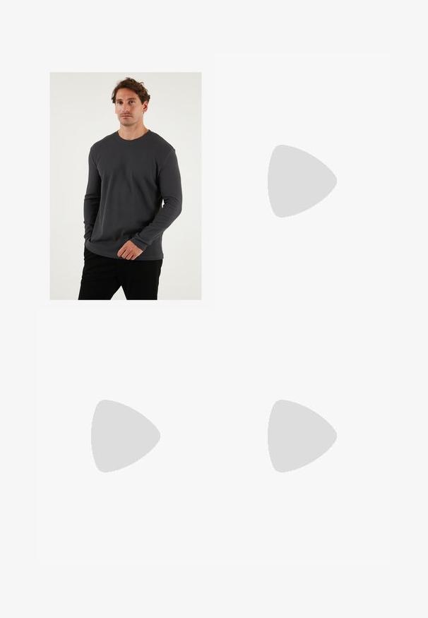 Graues, geripptes Langarm-T-Shirt mit Rundhalsausschnitt, strukturierter Stoff und taillierter Passform, kombiniert mit schwarzen Hosen vor neutralem Hintergrund.; Weite blaue Denim-Jeans mit einer ausgewaschenen Optik, Fünf-Taschen-Design und einer Knopfverschluss. Ausgestattet mit Gürtelschlaufen und gestickten Details.; Braunfarbener Sandale mit zwei Riemen und Kupfer-Ü berschlägen, Korkfußbett und Gummisohle. Schlankes Design mit verstellbaren Riemen für eine optimale Passform.; Silberner Anhänger mit einem Wellenmotiv, das mit dem Gesicht eines Löwen verwoben ist, hängt an einer massiven Kette. Die strukturiert Oberfläche verleiht zusätzliche Details.