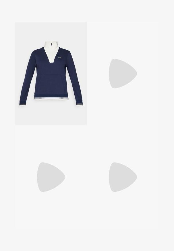 Mornarji polovični zadrga pulover iz teksturirane tkanine, z belim ovratnikom in manšetami, kenguru žepom ter zelenim logotipom Lacoste.; Bela bombažna majica s krožnim izrezom, kratkimi rokavi in majhnim mornarsko modrim logotipom na levem prsnem delu. Gladka tekstura, sproščen design.; Bela plisirana krila s temno modrim pasom in robom. Ima mehak material z vodoravnimi črtami na pasu, zasnovan za udobje.; Bela športna obuvala iz mrežastih in sintetičnih materialov, z dodanimi sivo odtenki in vezalkami, teksturirano podplat, ukrivljen dizajn in podrobnost logotipa.