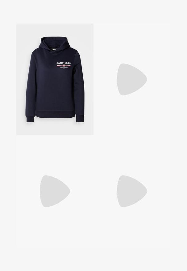 Námořnická modrá mikina s kapucí vyrobená z měkké tkaniny, zdobená bílým textem "GANT 1949" a pruhovaným grafickým detailem v červené a bílé.; Tmavě modré džíny s širokým střihem vyrobené z denimové tkaniny, s vysokým pasem, oranžovým prošíváním, pěti kapsami a zapínáním na knoflík.; Bílé nízké tenisky s černým patním tabem, platformovou podrážkou, tkaničkami a logem Calvin Klein "CK" na boku.; Stříbrné kruhové náušnice s texturovaným designem a vertikálními drážkami. Kulatý tvar s pevným uzávěrem. Hladký povrch.