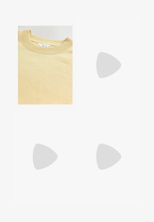 Crème-kleurige sweatshirt met een geribbelde ronde hals. Zachte textuur en gladde stof, met een label met de vermelding "NEXT" aan de binnenkant.; Zwarte sweatpants met een elastische tailleband, cuffed enkels en een klein wit Nike-logo aan de linkerkant. Gemaakt van een zachte, textiele stof.; Zwarte sportieve schoen met een textuurstof bovenkant, witte Nike swoosh en dikke witte zool. Beschikt over een trekhaak op de hiel voor gemakkelijk aan- en uittrekken.; Zwarte plastic zonnebril met groene lenzen, vierkante montuur, zilveren accent op de wenkbrauw en een gestructureerde tempel. Merken vermeld op de binnenkant van de arm.