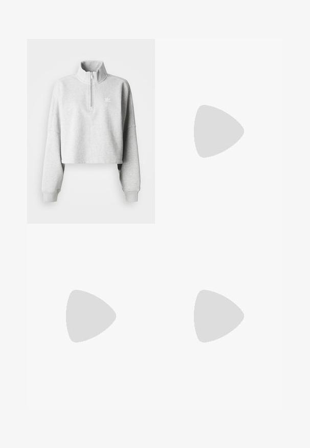 Jasnoszary krótki sweatshirt z wysokim kołnierzem i półzamkiem. Posiada luźne rękawy oraz małe białe logo na piersi. Materiał mieszany z bawełną.; Szerokie niebieskie dżinsy z wysokim stanem, pięcioma kieszeniami i kontrastowym przeszyciem. Wykonane z wytrzymałego materiału bawełnianego o gładkiej fakturze.; Brązowe zamszowe sneakersy z białymi akcentami i sznurówkami. Gumowa, brązowa podeszwa. Noszone z białymi skarpetkami w czarne paski. Zielona teksturowana podłoga.; Białe okulary przeciwsłoneczne o wyrazistym, przerośniętym designie i lustrzanych soczewkach, charakteryzujące się gładkimi plastikowymi oprawkami i akcentowanymi krzywiznami.