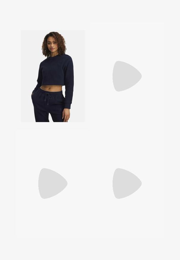 Felpa blu navy a bum short in morbido tessuto con maniche lunghe, caratterizzata da un collo tondo e dettagli ricamati discreti. Abbinata a pantaloni coordinati.; Leggings flared neri a coste con una vita alta, caratterizzati da un piccolo logo Adidas bianco sul lato sinistro superiore. Tessuto morbido.; Scarpa slingback in pelle nera con punta affilata, tacco basso e design a taglio sui lati. Texture liscia con un aspetto elegante.; Borsa a spalla bianca realizzata in materiale morbido, con un ritaglio ovale e un design a tracolla ampia. Semplice e moderna, senza hardware visibili.