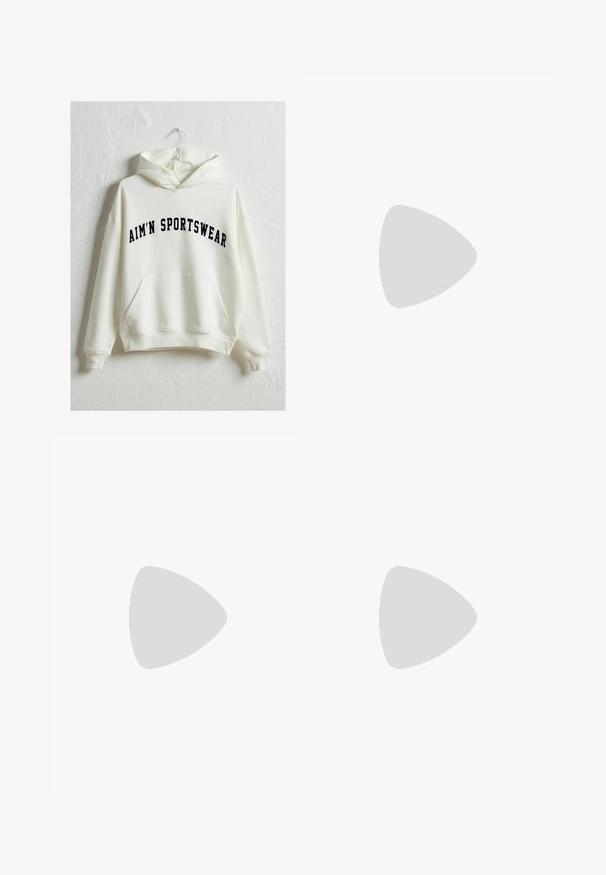Krém színű kapucnis pulóver elülső zsebével és navy színű, íves stílusú "AIM'N SPORTSWEAR" felirattal. Puha anyag, lazább szabás.; Fekete háromnegyedes leggings, rugalmas anyagból készült, magas derékkal és látható minták vagy fémalkatrészek nélkül.; Fehér hálós sportcipők ezüst részletekkel és texturált talppal, egy piros felületen elhelyezve, kockás nadrággal párosítva.; Szőtt szalmából készült táska, széles, kúpos formával, két fekete bőrkarral. Természetes bézs szín, texturált felülettel.
