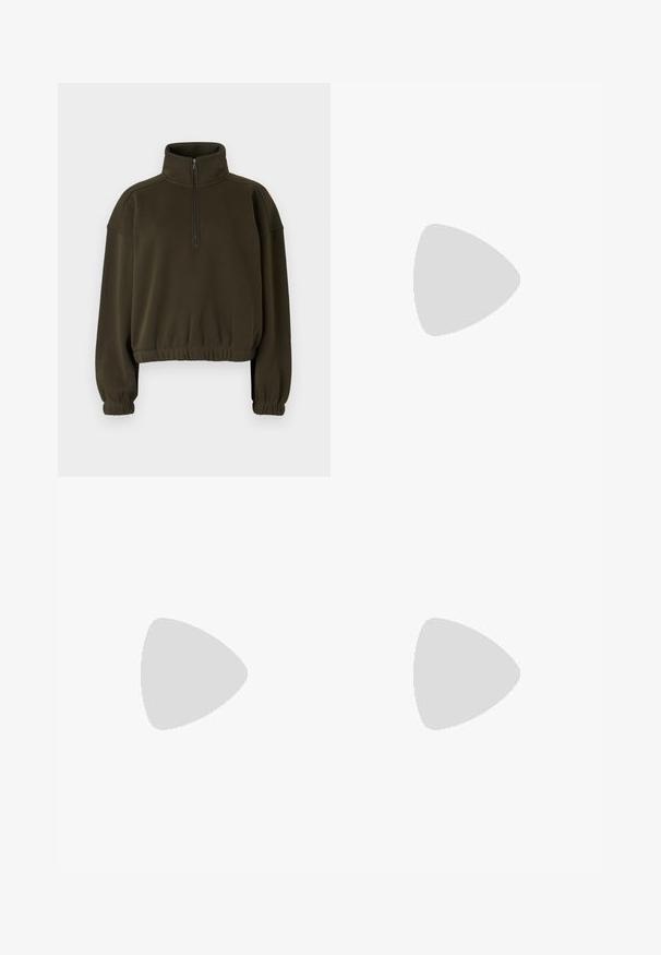 Olive green cropped sweatshirt made of soft fabric, featuring a high collar, half-zip closure, and elasticated cuffs and hem.; Beige corduroy trousers with a loose fit, featuring a drawstring waist, two front pockets, and vertical ribbed texture.; Light grey sneaker made of suede and mesh, featuring three white stripes, round toe, and a gum rubber sole. Gold logo accent near laces.; Green tank top with lace detail at the shoulder and neckline, featuring a fitted design and soft fabric. Paired with light-colored trousers.