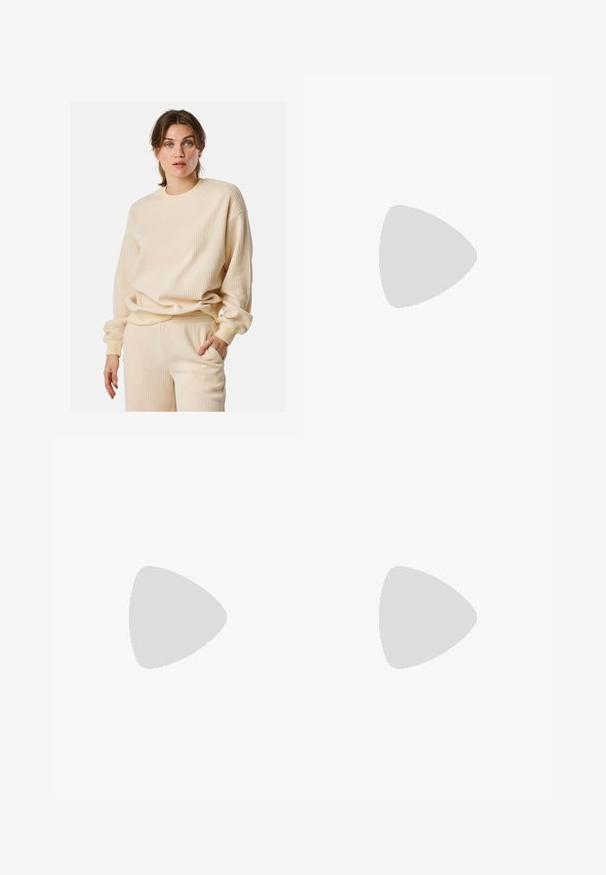 Felpa beige a costine con maniche lunghe, colletto rotondo e vestibilità ampia. Il materiale sembra morbido e strutturato, creando interesse visivo.; Top corto atletico nero con zip frontale, dettagli in rete e un design aderente. Realizzato in tessuto elasticizzato e traspirante. Logo Nike sul davanti.; Leggings cropped neri realizzati in tessuto elasticizzato, con vita alta e texture liscia, senza motivi o componenti visibili.; Scarpe da ginnastica bianche con tomaia in rete testurizzata, suola ammortizzata e sottili dettagli grigi. Comprendono il branding e una linguetta sul tallone per una facile calzata.