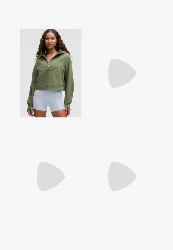 Jauna moteris su garbanotais plaukais, vilkinti aliejaus žalumo trumpą gobtuvą ir baltas aukšto liemens sportines šortus, stovi prieš vienodą foną.; Juodas sportinis liemenukas su prigludusia forma, plačiomis petnešomis ir tinklo apdaila priekyje. Lygus paviršius ir minimalūs siūlai. Nike logotipas apačioje.; Juodos leggingos, pagamintos iš lygios, tamprios medžiagos. Aukštas liemuo, be matomų raštų ar akcentų. Tvirtai priglunda prie kūno nuo liemens iki kulkšnies.; Baltos sportinės bateliai su rožiniais akcentais, aerodinamiškas dizainas, tekstūruotas tinklinis viršus ir lankstus gumos padas. Apima logotipą ir kilpą.