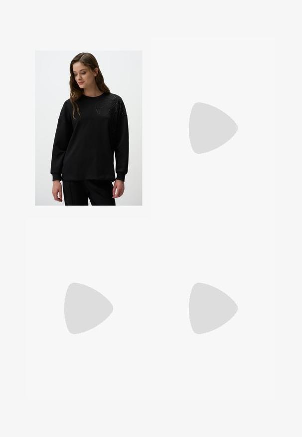 Zwarte sweatshirt met lange mouwen, ronde halslijn, met een decoratief patroon van kleine studs op de bovenste linkerzijde. Zachte textuur.; Lichtbeige wijde broek met een denim tailleband, voorzien van twee knopen en geplooide details aan de voorkant. Gladde textuur en ontspannen pasvorm.; Sportschoenen met een witte leren bovenkant, grijze suède neus en drie zwarte strepen. Bevat een blauw logo op de tong en een gestructureerde rubberen zool.; Schildpadbril met een rechthoekige vorm, groengetinte lenzen en gepatterde acetaat montuur. Kenmerkt metalen accenten nabij de lenzen.