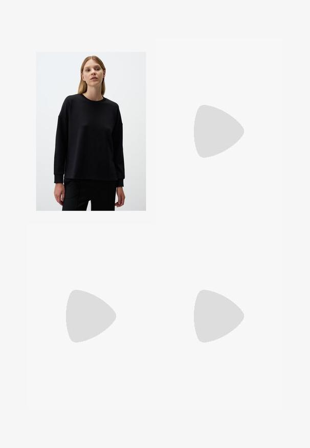 Felpa nera con maniche lunghe, scollatura a costine, vestibilità comoda, texture morbida e design minimalista. Indossata con pantaloni neri.; Pantaloni a gamba larga in tessuto grigio scuro, dotati di chiusura con bottone, pieghe frontali e passanti per cintura. Texture liscia con un design su misura.; Scarpe sportive con tomaia in pelle bianca, punta in suede grigia e tre strisce nere. Presentano un logo blu sulla linguetta e una suola in gomma testurizzata.; Borsa tote in pelle nera con una forma ampia e angolare. Presenta manici superiori doppi e una tracolla regolabile con un accento in metallo dorato.