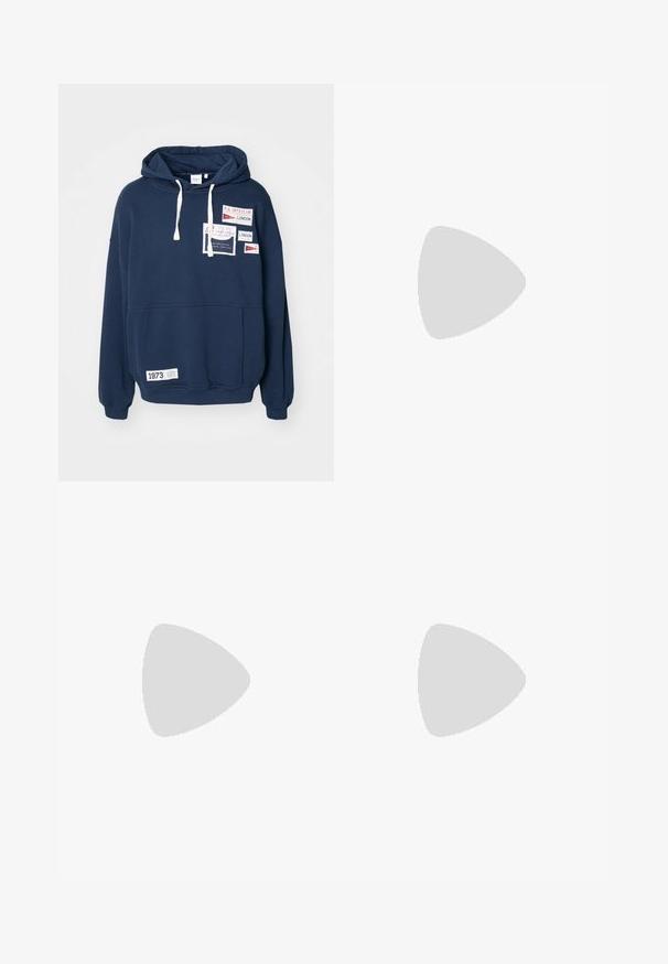 Felpa con cappuccio blu navy, maniche lunghe, tasca frontale a sacca e numerosi toppe in tessuto con scritte in rosso e bianco.; T-shirt bianchi in cotone, maniche corte, design a collo tondo, texture liscia, impilati in fila, con un sottile marchio all'altezza del collo.; Pantaloni della tuta marroni con vita elastica; presenta due strisce bianche sui lati e un logo sulla coscia sinistra; tessuto morbido e design a gamba affusolata.; Sneakers bianchi in pelle con punta in suede grigia, tre strisce orizzontali bianche, accenti blu e suola in gomma marrone. Dettaglio testurizzato sulla suola.