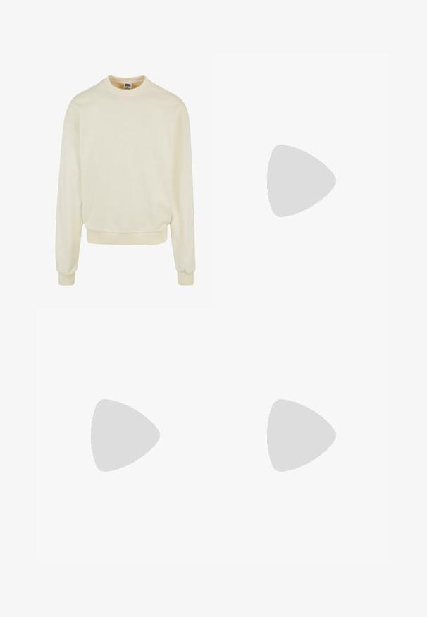 Cremfarbener Sweatshirt aus weichem Stoff mit Rundhalsausschnitt, langen Ärmeln sowie gerippten Bündchen und Saum. Keine Muster oder Grafiken.; Weißes Kurzarm-T-Shirt mit Rundhalsausschnitt und lockerer Passform, gefertigt aus einem glatten Baumwollmischgewebe. Keine Muster oder Verzierungen.; Hellblaue Jeans aus Denim mit geradem Schnitt, sichtbaren Nähten, fünf Taschen-Design und einem Knopfverschluss an der Taille.; Nike-Sneaker in Weiß mit silbernen Akzenten, ausgestattet mit strukturierten Paneelen und Perforationen. Kombiniert mit grauen gerippten Socken, vor einem gelben Hintergrund.
