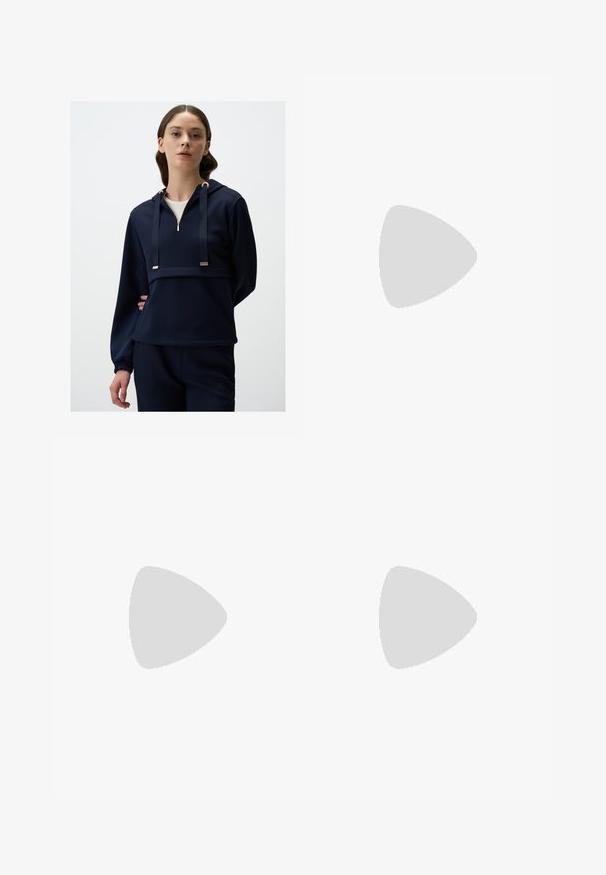 Felpa blu navy realizzata in tessuto morbido; presenta una zip frontale, dettagli in metallo dorato e polsini elasticizzati per una vestibilità confortevole.; Pantaloni ampi marroni con una texture liscia, caratterizzati da una vita alta e pieghe frontali. Il tessuto è leggero e scorre liberamente.; Sandal in pelle marrone con cinturini incrociati, chiusura con cinturino alla caviglia e suola piatta con dettagli di cucitura minimi.; Borsa in pelle marrone con parte superiore arricciata e tracolla a catena. Texture liscia con finitura lucida e dettagli di cucitura sottili sui lati.