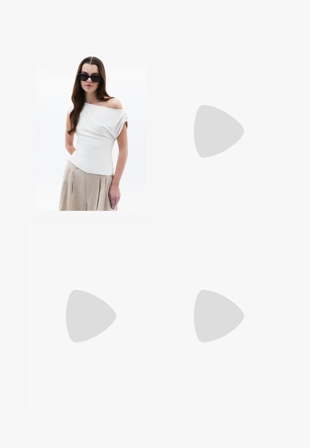 Top blanc à épaules dénudées avec détail de tissu drapé, manches courtes à revers, associé à un pantalon plissé beige taille haute.; Pantalons larges taille haute avec des rayures verticales ondulées blanches et marron foncé, bouton frontal, fermeture éclair et poches latérales.; Chaussure plate blanche avec un design en maille, un bout pointu et une semelle basse et plate. Tige texturée avec une doublure lisse et une bordure de contraste subtile.; Sac à épaule en cuir marron au design décontracté, avec des accessoires en or et des coutures blanches contrastantes, tenu par une personne portant des vêtements en denim.