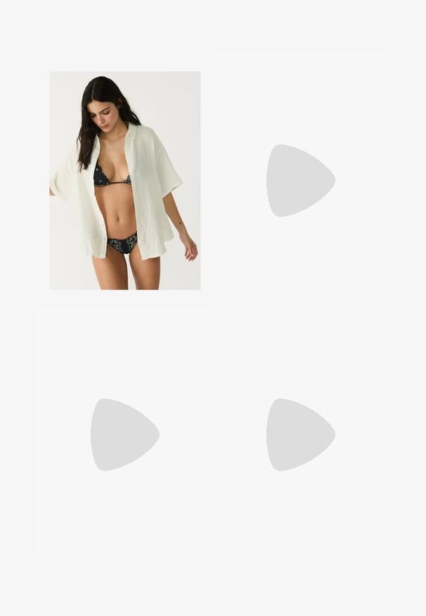 Biała, oversize koszula z guzikami, wykonana z fakturowanej tkaniny, noszona na otwarte nad czarnym bikini z wzorem. Krótkie rękawy i luźny krój.; Długa, warstwowa spódnica w bogatym brązowym kolorze, wykonana z lekkiego materiału. Posiada elastyczny pas i swobodny krój dla łatwości ruchów.; Beżowe klapki z odkrytymi palcami, płaską podeszwą i dekoracyjnymi metalowymi łańcuszkami na pasku. Gładki materiał z minimalną teksturą.; Portfel na nadgarstek marki Michael Kors w beżowej, pokrytej płótnem, z powtarzającym się wzorem logo MK, złotym okuciem i odpinanym łańcuszkowym paskiem.