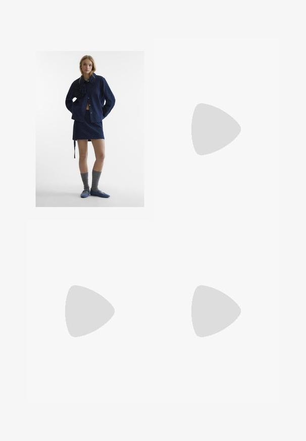Giacca a fantasia navy con dettaglio floreale, mini gonna coordinata, calze alta fino al ginocchio grigie e scarpe blu slip-on. Texture del tessuto liscia.; Jeans a gamba larga di colore azzurro chiaro, realizzati in denim. Presentano un alto punto vita, design a cinque tasche e chiusura con bottone. Taglio dritto con orlo pulito.; Stivali neri al ginocchio in pelle liscia, con una spessa suola platform e tacco a blocco, dotati di cuciture decorative lungo i bordi.; Blazer marrone con ampi revers sopra una camicia a motivi con design geometrici in bianco, nero e rosso. Grandi occhiali da sole neri completano il look.