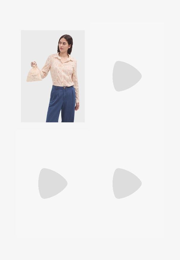 Camicia beige con bottoni, decorata con schizzi e motivi arancioni, abbinata a pantaloni strampalati blu a righe verticali. Il modello tiene in mano una piccola borsa di stoffa.; Pantaloni neri realizzati in tessuto morbido, caratterizzati da vita alta, gambe larghe, pince frontali e classiche passanti per cintura. Non ci sono tasche laterali visibili.; Sandali neri in pelle con dettagli in oro, caratterizzati da più cinghie e una suola piatta per un design open-toe.; Borsa a tracolla in pelle marrone con chiusura a pattina, hardware color oro, tracolla e una finitura liscia. Forma rettangolare compatta.
