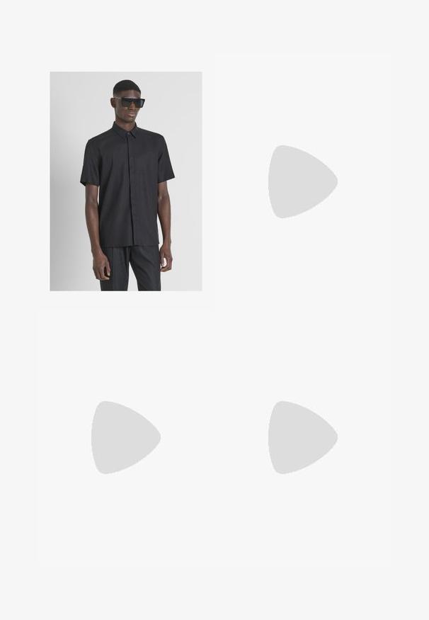 Camisa negra de botones de manga corta, hecha de una tela texturizada, con un cuello clásico y un dobladillo recto. Lleva puestas gafas de sol oscuras.; Pantalones de lino color beige claro con cintura elástica y cordón. Diseño de pierna recta con una textura suave y ligero ajuste en los tobillos.; Chancla negra con correas texturizadas, suela plana y borde dentado. Fabricada en goma con un acabado suave y un diseño minimalista.; Gafas de sol de plástico negro con lentes verdes, montura cuadrada, acento plateado en la ceja y brazos texturizados. Marca indicada en el brazo interno.; Pulsera de cuentas negras que presenta dos hileras de cuentas mates con un acento metálico rectangular. Textura suave, forma uniforme, diseño minimalista.