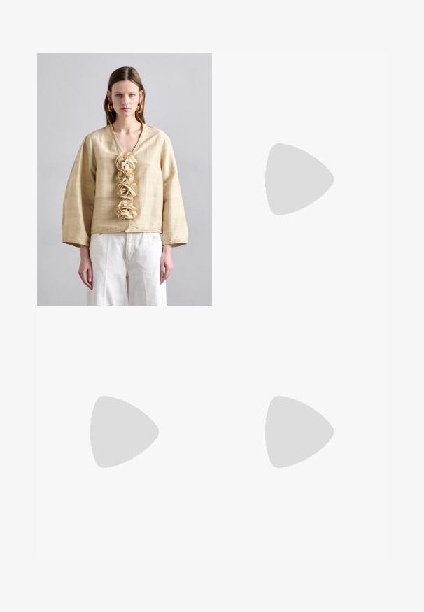 By Malene Birger MINEAS - Bluza - sea mist; Bež hlače širokih nogavica od glatke tkanine, s visokim strukom i suptilnim prednjim naborima. Bez džepova ili vidljivih metalnih detalja.; Bež sandala s visokom potpeticom, s pletenom teksturom, ukrašena cvijetom i remenom oko gležnja. Kvadratna potpetica dodaje stabilnost.; Bež torba na rame od kože s preklopom, srebrnim detaljima i odvojivim remenom. Glatka tekstura i jednostavan pravokutni oblik.
