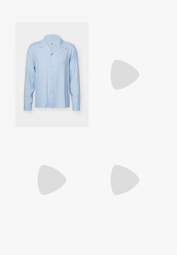 Lichtblauwe, lange mouwen, button-up shirt met een camp collar, gemaakt van een soepele stof. Heeft een rechte snit en blauwe knopen.; Lichtgrijze, wijde sweatpants van zacht materiaal. Heeft een elastische tailleband en zijzakken. Gladde textuur met een strak ontwerp.; Zwarte suède sneakers met witte accenten, voorzien van een gouden logo. Gemaakt met lichtblauwe spijkerbroek en geplaatst op een textuur blauwe ondergrond.; Zwarte rechthoekige zonnebril met groene lenzen, matte afwerking, subtiele hardwareaccenten en een gegraveerd logo op de slaap.
