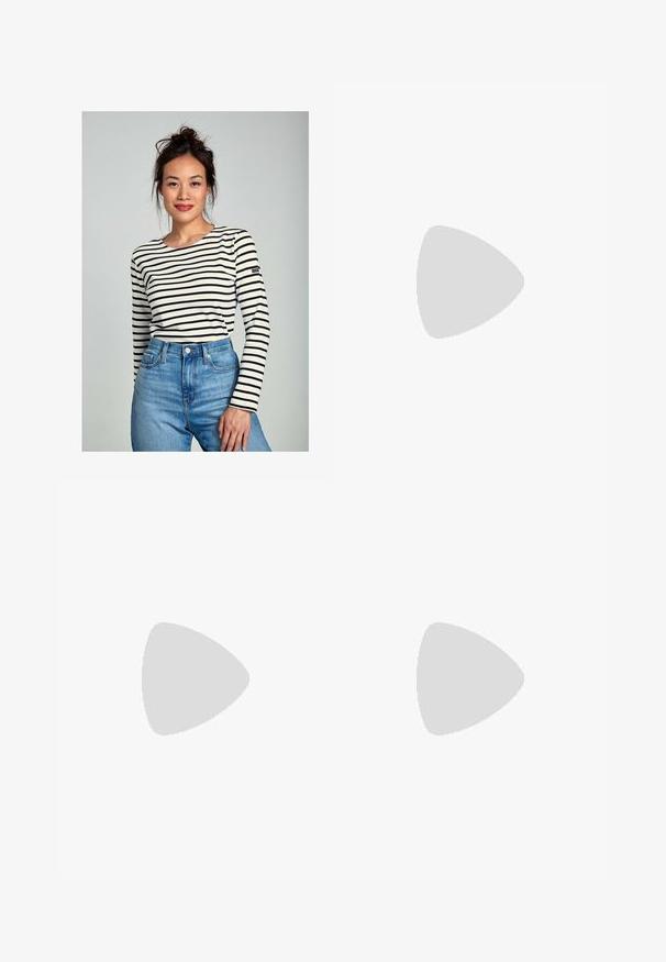 Langsleeve, crew neck top in crème met marineblauwe horizontale strepen. Gepaard met high-waisted denim jeans. Bevat een klein logo op de mouw.; Zwarte cropped broeken met een losse pasvorm, elastische tailleband en twee voorkruiken. De stof heeft een gladde textuur met een licht glanzende afwerking.; Zwarte lederen instappers met een platte hak, met een decoratieve gouden hardware detail aan de voorkant en een gladde textuur.; Zwarte handtas met gestructureerde vorm, gladde textuur en een metalen sluiting. Gecombineerd met brede zwarte broeken en sandalen met open teen op een houten vloer.