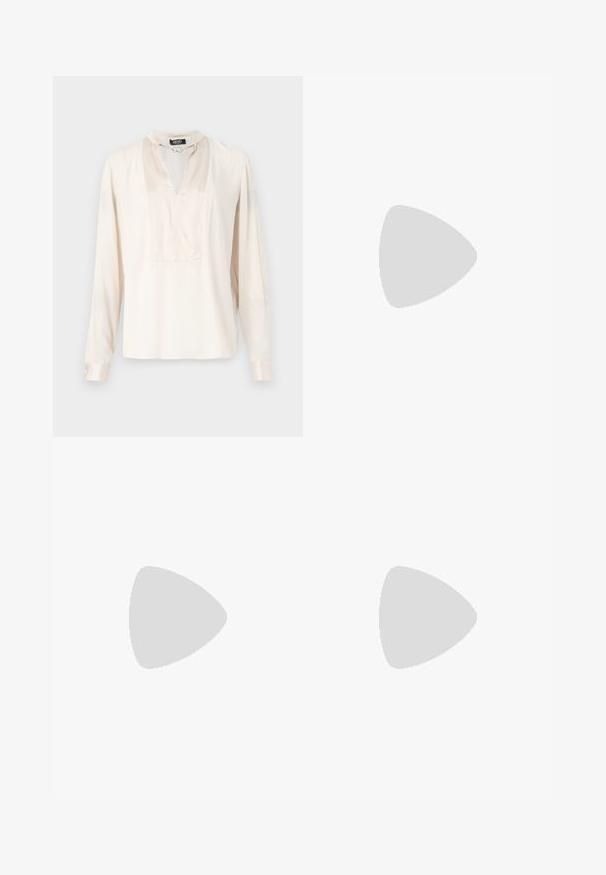 Langärmlige, cremefarbene Bluse aus Satin, mit hohem Kragen und Kettenakzent sowie V-Ausschnitt, in lockerer Passform.; Hellblaue Jeans mit hoher Taille, weitem Bein und einem verwaschenen Finish. Verfügt über einen klassischen Fünf-Taschen-Stil und einen Metallknopfverschluss.; Braune Wildleder-Sneaker mit weißen Akzenten und Schnürsenkeln. Gummisohle in Kautschuk-Optik. Getragen mit weißen Socken, die schwarze Streifen haben. Grüner strukturierter Fußboden.; Schwarze Leder-Hobo-Tasche mit einem lässigen Design, breitem Schultergurt und glatter Textur. Verfügt über einen seitlichen Reißverschluss.