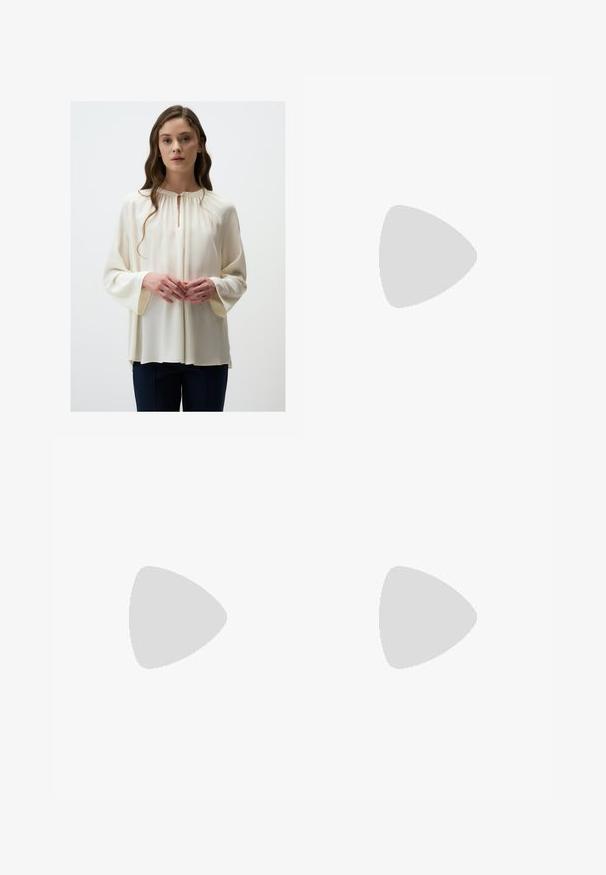 Blouse crème avec un col rond et un détail en fente, dotée de longues manches larges et d'une texture douce et fluide. Associée à un pantalon sombre.; Pantalons larges marron avec une texture lisse, dotés d'une taille haute et de plis à l'avant. Le tissu est léger et tombe de manière fluide.; Sandales à talons vernies noires avec un bout carré, des sangles autour de la cheville et des boucles en argent. Dotées d'un talon bloc épais pour plus de stabilité.; Sac bandoulière en cuir marron avec une forme incurvée, quincaillerie dorée et un accent en boucle. Comprend une bandoulière détachable.