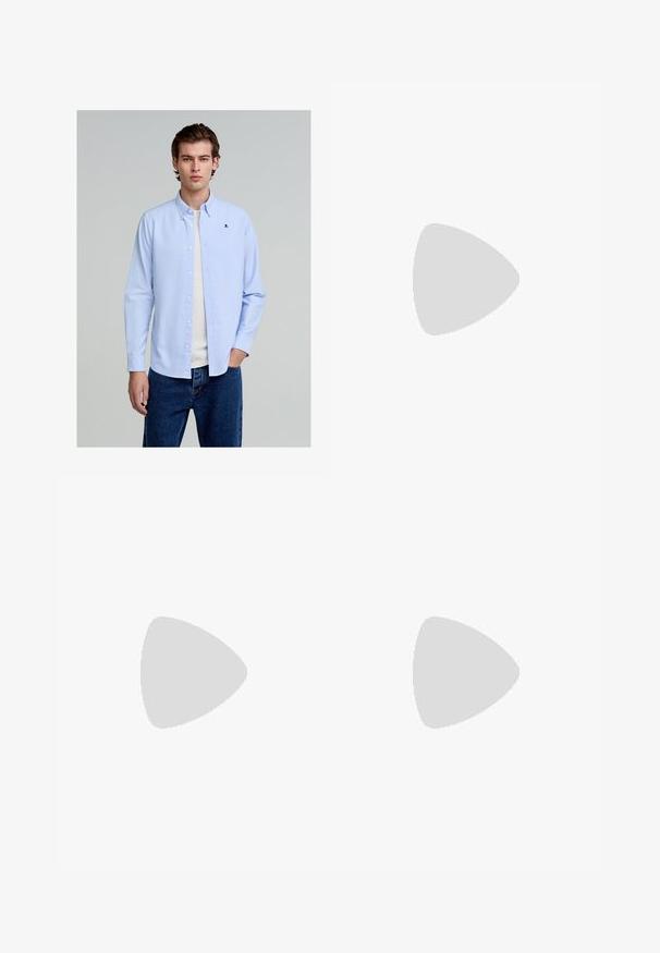 Jasnoniebieska koszula z długim rękawem wykonana z bawełny, z małym czarnym logo czaszki na piersi, w połączeniu z niebieskimi dżinsami.; Czarne legginsy z elastycznym paskiem, dwiema tylnymi kieszeniami i luźnym krojem. Gładka faktura materiału i prosty krój nogawki.; Brązowe zamszowe buty z białą gumową podeszwą, zawiązywane, z metalowymi oczkami i kontrastowym przeszyciem wzdłuż krawędzi.; Czarne okulary przeciwsłoneczne z prostokątnymi oprawkami, szarymi soczewkami i wycięciem w mostku. Gładki, błyszczący materiał plastikowy, z wąskimi zausznikami.