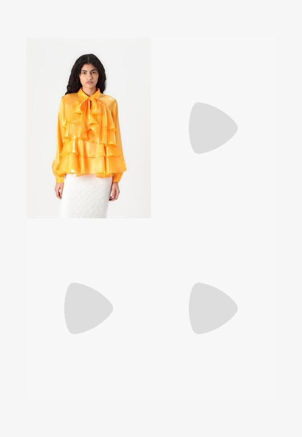 Gelbe Satinbluse mit Rüschenschichten, Schleifenkragen und langen Ärmeln. Die Textur ist glatt und glänzend. Getragen über einem weißen strukturierten Rock.; Rotes Kleid mit V-Ausschnitt, 3/4-Ärmeln und Raffung an der Taille und am Rücken. Der Stoff wirkt glatt und leicht.; Weiße hochwertige Leinensneaker mit schwarzer Gummisohle, vorderem Gummizehenschutz und sechs Ösen für Schnürsenkel, die ein sauberes, minimalistisches Design aufweisen.; Rote Lederhandtasche mit einem kantigen, geometrischen Design. Verfügt über einen verstellbaren Schulterriemen und einen Klappenverschluss mit genähten Details.