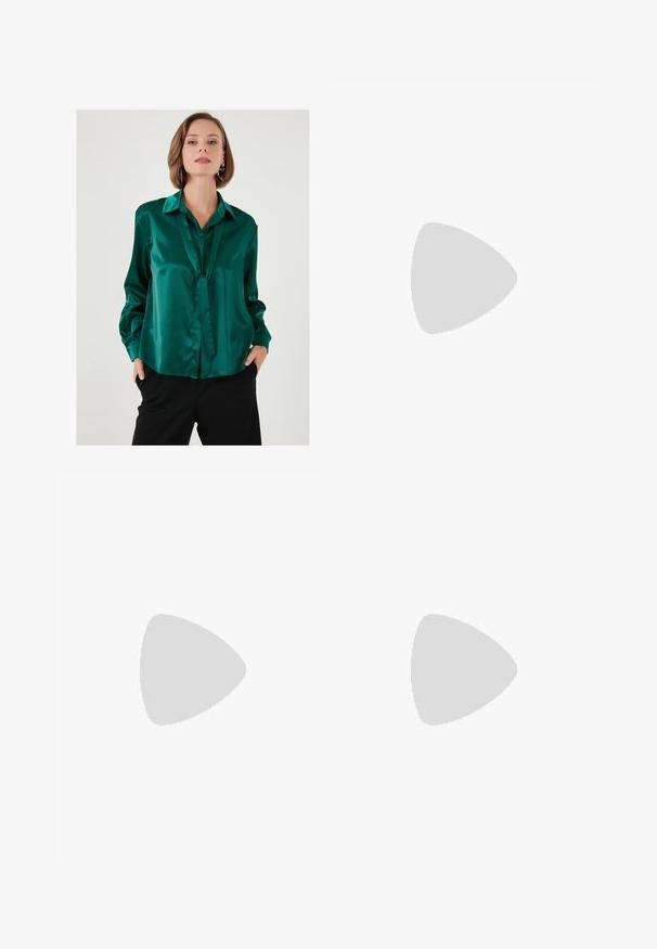 Blusa in satin verde smeraldo con colletto piatto, maniche lunghe e dettaglio annodato nella parte frontale. Tessuto liscio e vestibilità rilassata.; Jeans larghi marroni in denim, caratterizzati da una chiusura frontale con bottone, cinque tasche e dettagli di cucitura visibili.; Scarpe slingback in pelle verniciata bordeaux con punta appuntita, caratterizzate da due cinturini regolabili con fibbie e dettagli in metallo argentato.; Borsa in pelle bordeaux con un design morbido e arricciato e una forma arrotondata. Il manico è fissato, mostrando una texture liscia.