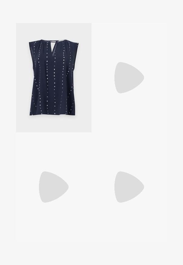 Navyblaues ärmelloses Oberteil mit V-Ausschnitt und Schlitzdetails, das weiße Punktmuster hat, die vertikal über den Stoff angeordnet sind.; Schwarze weite Hosen mit hoher Taille, Knopfdetails am Bund und vorderen Falten.; Schwarze Lederloafers mit flachem Absatz, die auf der Vorderseite ein dekoratives goldfarbenes Hardware-Detail und eine glatte Textur aufweisen.; Schwarze Handtasche mit strukturierter Form, glatter Textur und einem metallischen Verschluss. Kombiniert mit weiten schwarzen Hosen und offenen Sandalen auf einem Holzboden.