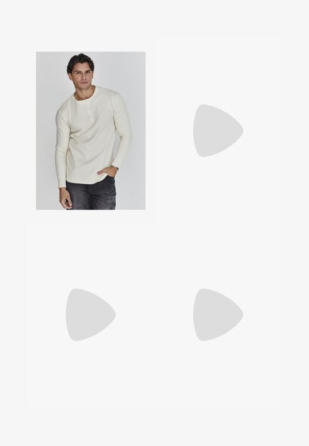 Camisa henley de manga larga en color crema, con cuello redondo, botonera de tres botones y puños ajustados, combinada con jeans oscuros.; Pantalones de rayas grises con un ajuste relajado, que presentan un cierre de botón, pasadores para cinturón y sutiles rayas azul claro en toda su superficie.; Zapatos de cuero negro con punta redondeada, diseño de cordones y suela gruesa y texturizada. Combinados con pantalones negros a medida y un suéter acanalado.; Gafas de sol de plástico negro con lentes verdes, montura cuadrada, acento plateado en la ceja y brazos texturizados. Marca indicada en el brazo interno.