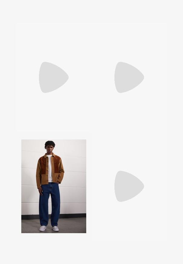 Hnědé tričko s krátkým rukávem vyrobené z měkké látky s kulatým výstřihem. Má volný střih a jednoduché detaily na lemu.; Muž stojící uvnitř, oblečený v hnědé kordové bundě se rezavými skvrnami, bílém tričku, volných modrých džínách a bílých teniskách.; Hnědé kožené mokasíny s kulatou špičkou, ozdobným šitím na přední straně a plochou gumovou podrážkou pro podporu a odolnost.; Brýle ve stylu želvoviny s obdélníkovým tvarem, zelenými skly a vzorovanými acetátovými rámy. Obsahují kovové akcenty poblíž skel.
