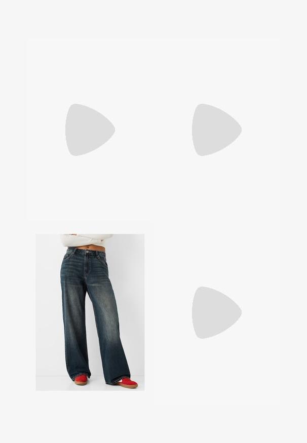 Weißes langärmliges Oberteil mit einem drapierten Design aus weichem Stoff. Mit einer gerafften Detail auf einer Seite und einem welligen Saum an der Unterseite.; Hellebige, dunkle Jeans mit weitem Bein, sichtbaren Nähten, fünf Taschen und einem blauen Waschfinish. Kombiniert mit roten Sneakern.; Braune Wildleder-Sneaker mit weißen Akzenten und Schnürsenkeln. Gummisohle in Kautschuk-Optik. Getragen mit weißen Socken, die schwarze Streifen haben. Grüner strukturierter Fußboden.; Beige Leder Umhängetasche mit kurvenförmiger Gestalt, umklappbarem Deckel, verstellbarem Tragegurt und Beschlägen in Goldoptik. Glatte Textur.