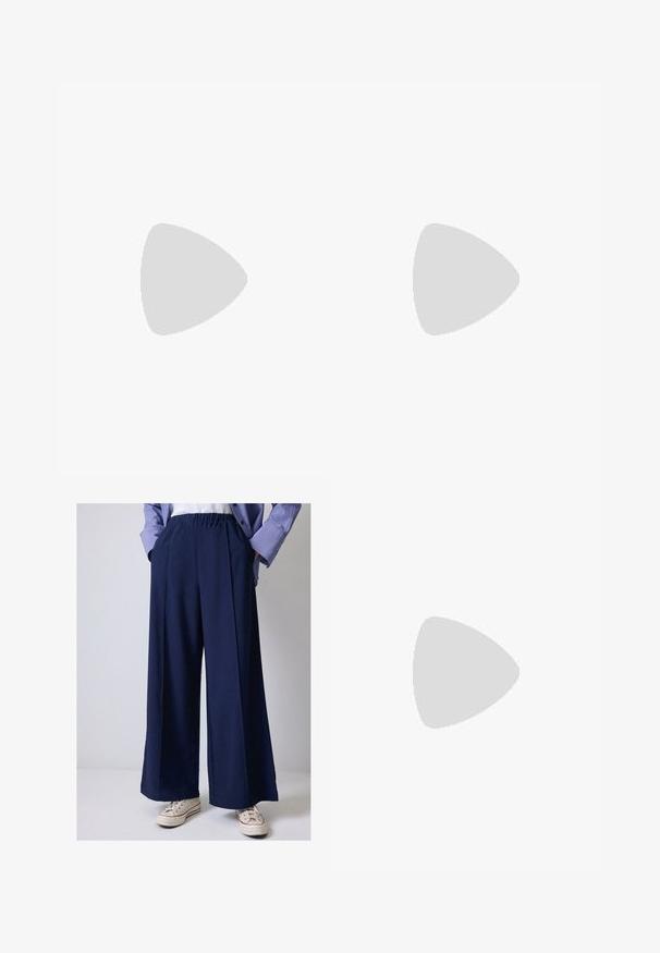 Sutien de sport albastru realizat dintr-un material elastic. Dispune de un gât semicircular, bretele late și o bandă elastică inferioară cu inscripția "7 DAYS ACTIVE" imprimată în argintiu.; Pantaloni largi de marina, cu talie elastică, având buzunare laterale și o textură de țesătură netedă. Asortați cu adidași albi.; Sandale negre din material fin, cu trei bretele ajustabile și catarame aurii, având o talpă plată cu textură antiderapantă.; Geantă tote din suede maro cu două mânere lungi, închidere prin șnur și un design minimalistic. Textură netedă și fără accente vizibile de hardură.