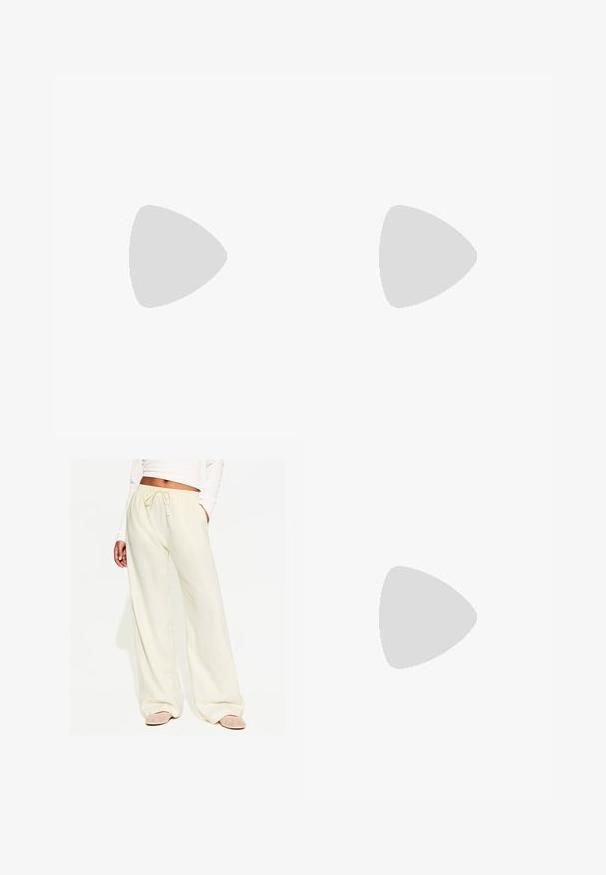 WE Fashion SINGLET - Top - beige; Široke svetlo rumene hlače z elastiko v pasu, ki imajo gladko teksturo in stranske žepke, v kombinaciji z dekorativnimi ravnimi sandali.; Sive športne čevlje iz semiša z belimi vezalkami, črnimi črtami in belim gumijastim podplatom. Imajo okroglo oznako na ježku in podplat iz gume.; Črne ovalne sončne očala s temnimi lečami, sijajnim plastičnim okvirjem in zlatimi poudarki na templjih.