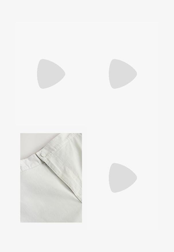 Bílá bavlněná tričko s krátkými rukávy. Obsahuje malou zelenou grafiku a černý text na levé části hrudníku. Klasický design s kulatým výstřihem.; Bílá bavlněná tkanina s knoflíkovým zapínáním v pase, s jemnou strukturou a šitými detaily podél švů.; Hnědé semišové boty s nízkým profilem, šněrovacím designem, gumovou podrážkou a kontrastními švy. Jednoduchý a funkční styl.; Černé obdélníkové sluneční brýle s tmavými skly, které mají charakteristický tvar a logo na straně. Nosí je osoba v zelené košili.